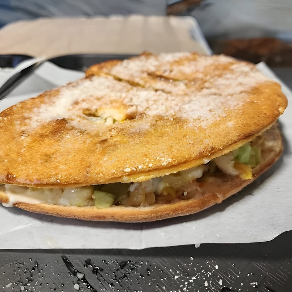 A golden-brown, sugar-dusted dessert pizza from Halal Pizza, filled with fruit and cream.